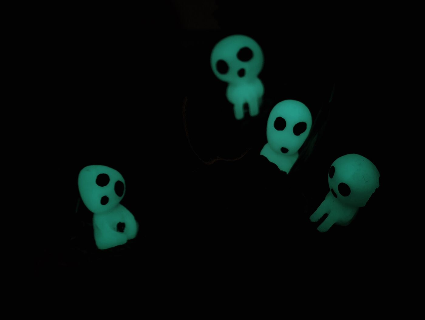 Kodamas de cerca junto a las hojas brillando en la oscuridad