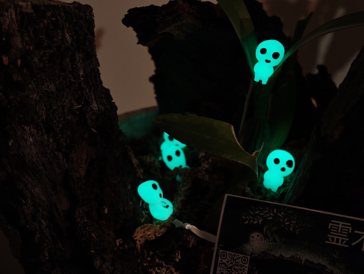 Kodamas en el tronco entre las orquídeas brillando en la oscuridad